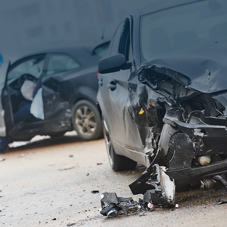 Crashed black car with significant frontal damage and debris scattered around, highlighting the aftermath of a severe vehicle accident.